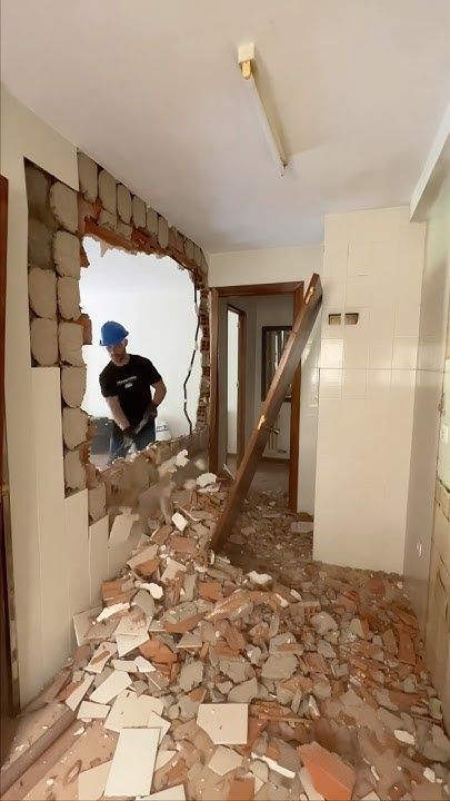 Obra de demolição de paredes com um trabalhador removendo uma parde com uma marreta