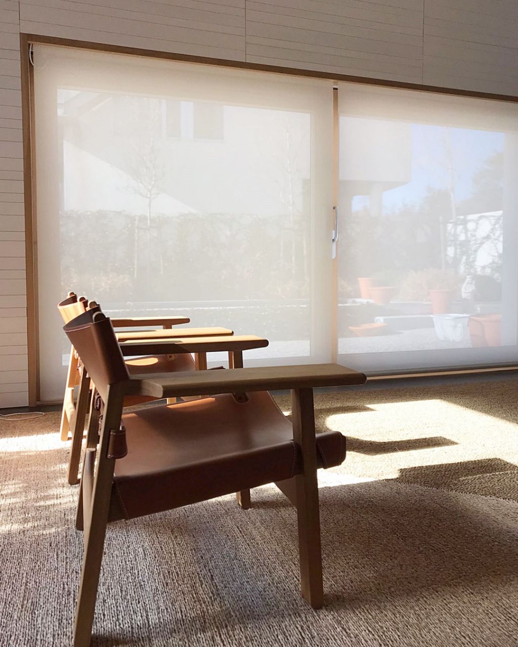 Persiana rolo screen técnico em living com poltronas — é possível ver o lado de fora de dentro